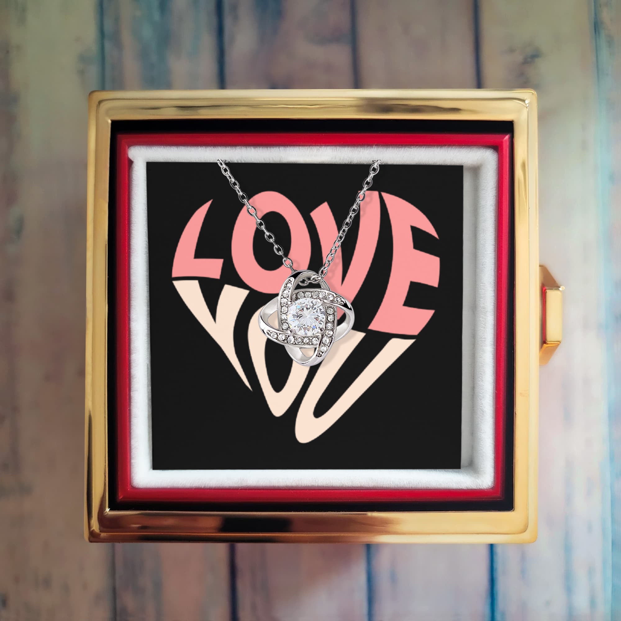 Imagine her reaction as she receives this beautiful Love Knot Necklace. Representing an unbreakable bond between two souls, this stunning pendant is adorned with premium cubic zirconia crystals, making it a timeless symbol of love and devotion. The luxurious box, featuring a meticulously preserved rose that never fades, adds an extra touch of love. With a simple turn of the gold knob, her breathtaking gift is revealed—making it the perfect sentimental gift for that special someone.